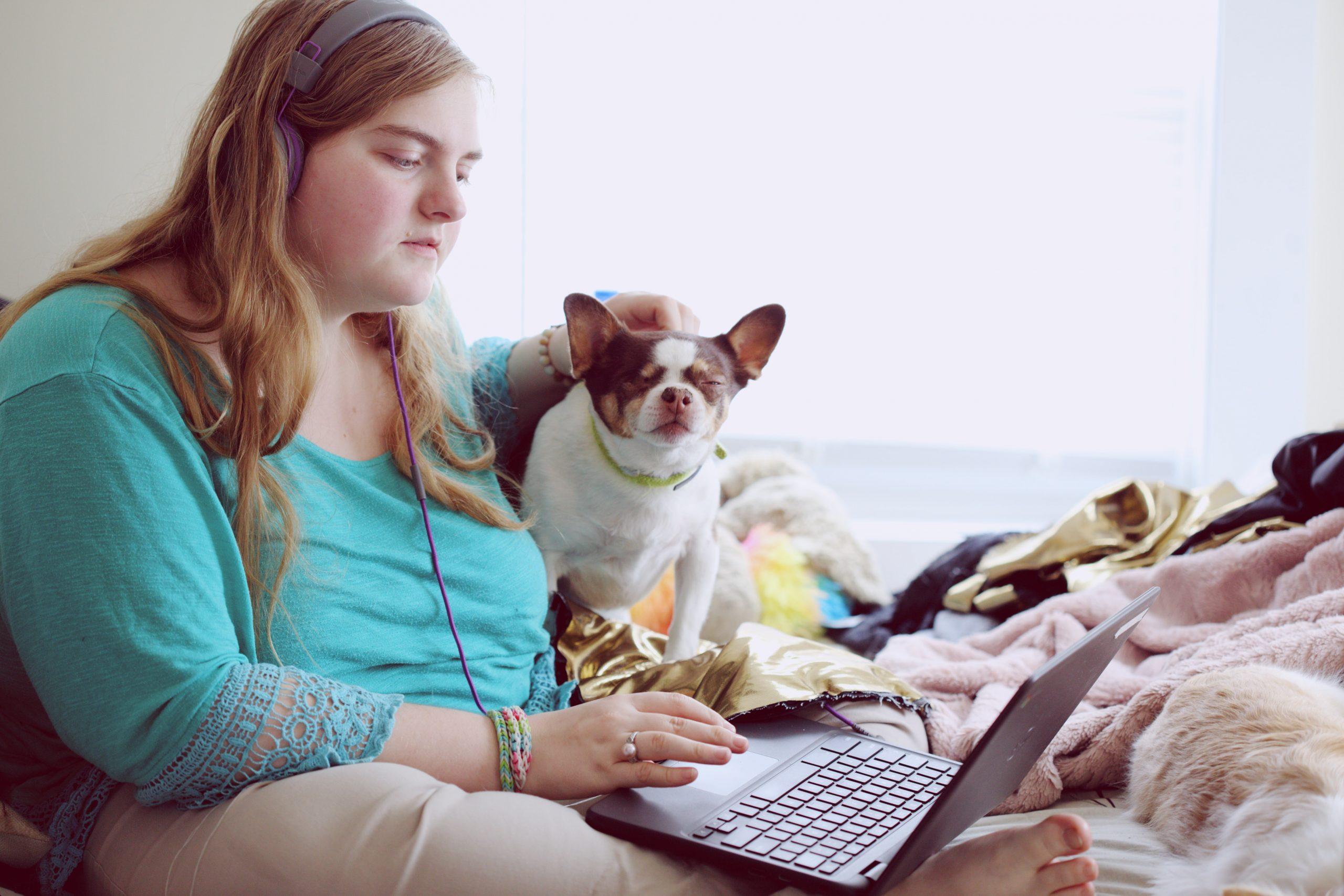 Young woman with autism using her laptop with dog beside her